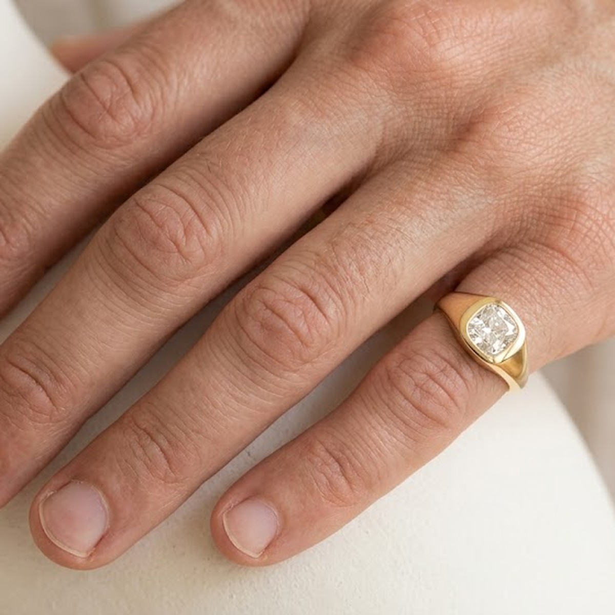 A gold signet ring with a diamond set flush in the face