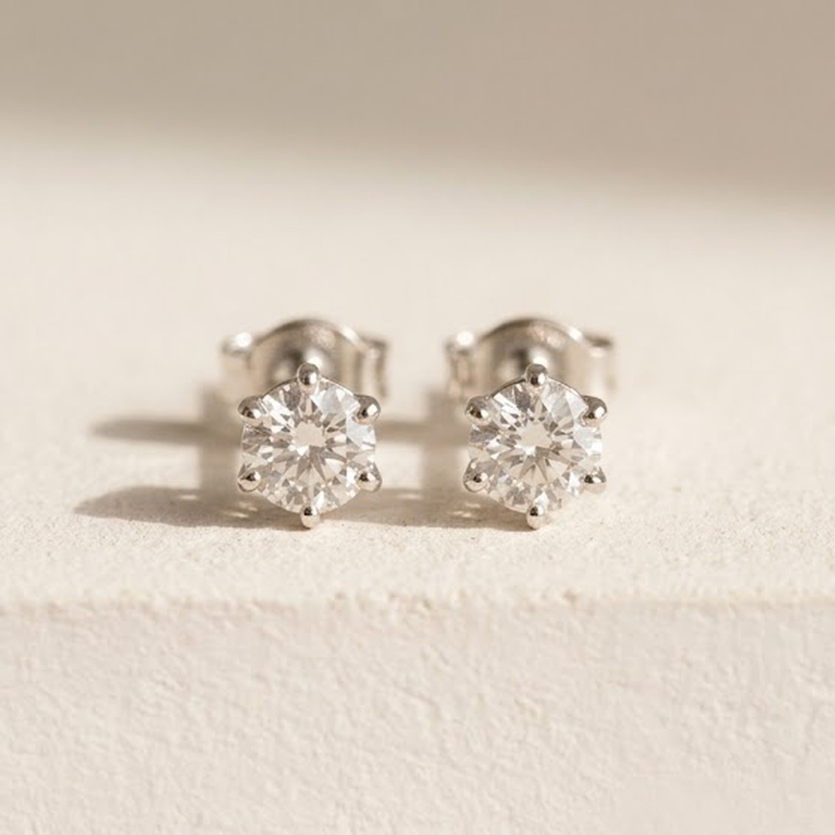 A pair of round-brilliant diamond studs, one commission, two stones